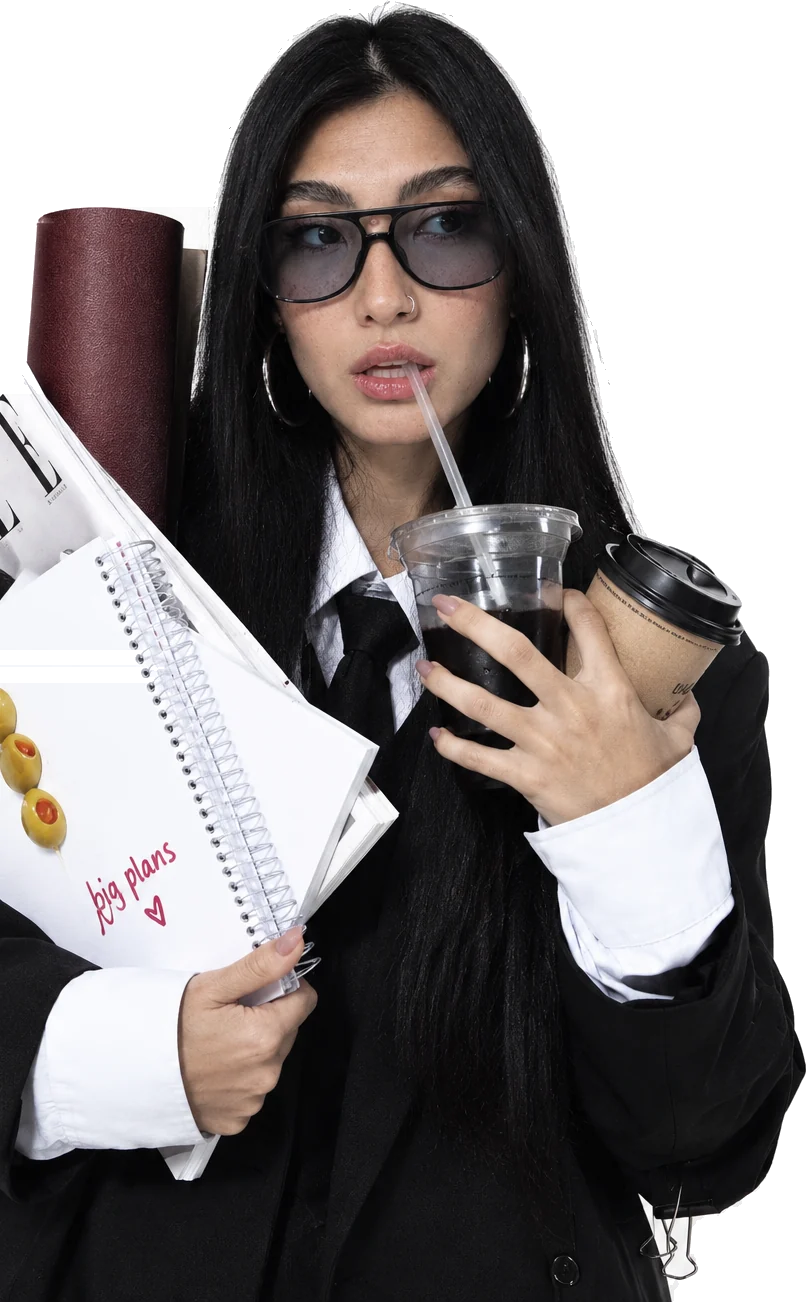 Camilla holding an iced coffee, a notebook and a stack of magazines